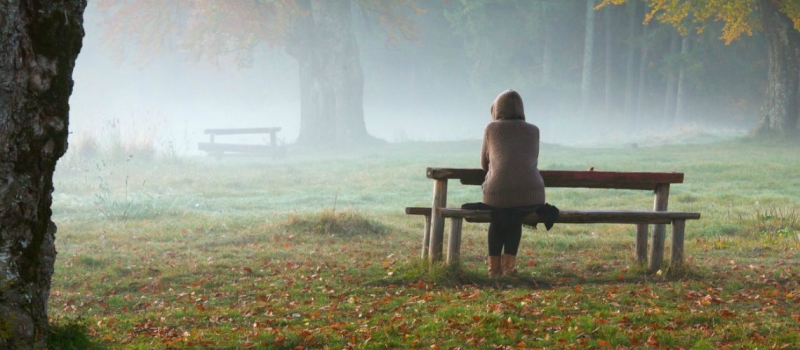 Woman relaxing on a bench in a foggy morning Woman relaxing on a bench in a foggy morning